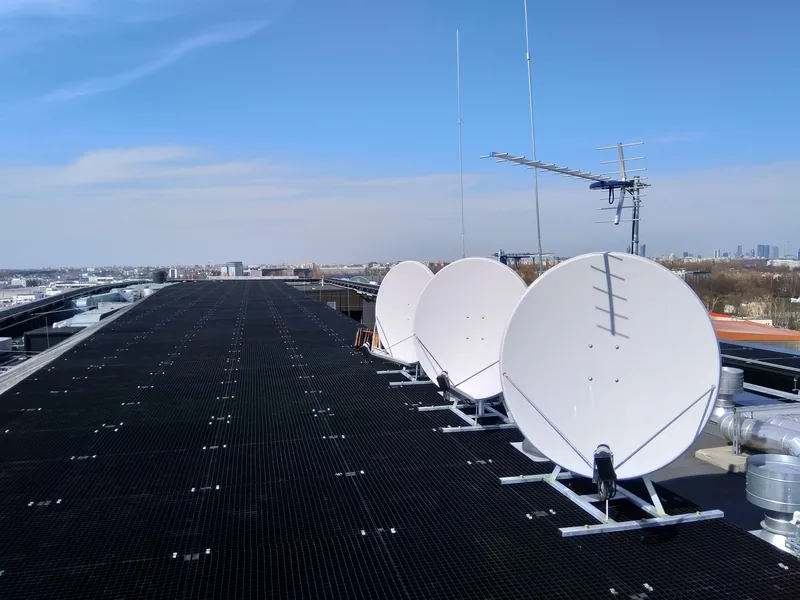 Instalacja anten satelitarnych na dachu hotelu — panorama miasta w tle